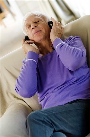 Senior man wearing headphones, sitting in an armchair Stock Photo - Premium Royalty-Free, Code: 6108-05856857