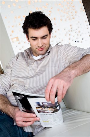 Homme assis sur un canapé, lisant un magazine Photographie de stock - Premium Libres de Droits, Code: 6108-05856813