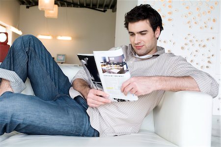 sitting room with people sitting - Man lying on a sofa, reading magazine Stock Photo - Premium Royalty-Free, Code: 6108-05856830