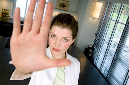 stopping - Young woman in a living-room, pointing at the camera Stock Photo - Premium Royalty-Free, Code: 6108-05856941