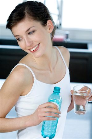 Jeune femme souriante tenant un verre et une bouteille d'eau minérale Photographie de stock - Premium Libres de Droits, Code: 6108-05856952