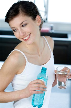 Young smiling woman holding a glass and a bottle of mineral water Foto de stock - Sin royalties Premium, Código: 6108-05856952