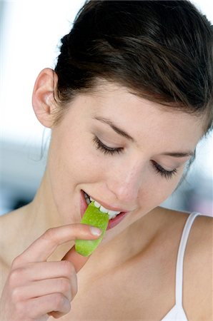 Portrait of a young woman eating apple slice Stock Photo - Premium Royalty-Free, Code: 6108-05856959
