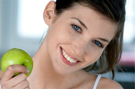 Portrait of a young smiling woman holding an apple Stock Photo - Premium Royalty-Free, Code: 6108-05856971