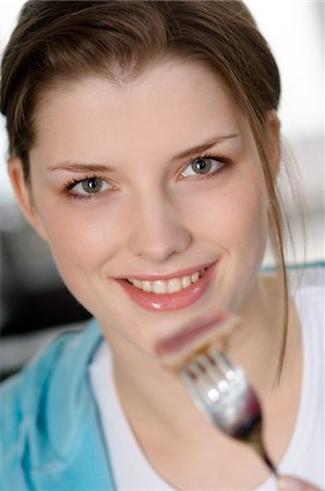 fork hand - Portrait d'une jeune femme souriante, manger de la viande Photographie de stock - Premium Libres de Droits, Code: 6108-05856985