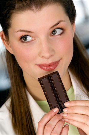 Portrait of a young woman holding chocolate bar Stock Photo - Premium Royalty-Free, Code: 6108-05856988