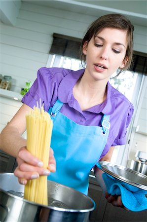 female with apron in kitchen - Woman cooking pasta Stock Photo - Premium Royalty-Free, Code: 6108-05857046