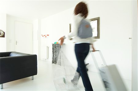 Woman carrying suitcase and birdcage in a living-room Stock Photo - Premium Royalty-Free, Code: 6108-05857097