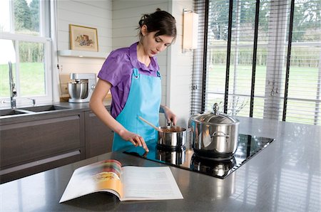 pequeno fogão portátil - Young woman cooking, recipe book Foto de stock - Royalty Free Premium, Número: 6108-05857013