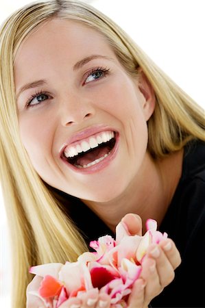 simsearch:6108-05861350,k - Portrait of a young woman smiling, holding petals flowers, indoors (studio) Fotografie stock - Premium Royalty-Free, Codice: 6108-05857342