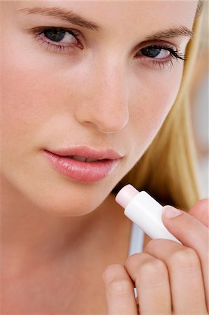 Portrait of a young  woman using a lip balm Stock Photo - Premium Royalty-Free, Code: 6108-05857351