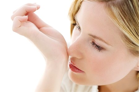 Portrait of a young woman smelling her wrist Stock Photo - Premium Royalty-Free, Code: 6108-05857358