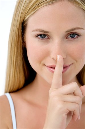 Portrait d'une jeune femme, doigt sur sa bouche Photographie de stock - Premium Libres de Droits, Code: 6108-05857301