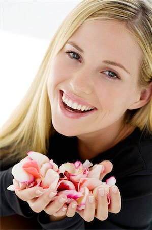 simsearch:6108-05857309,k - Portrait of a young woman smiling, holding flowers petals, indoors (studio) Foto de stock - Sin royalties Premium, Código: 6108-05857311