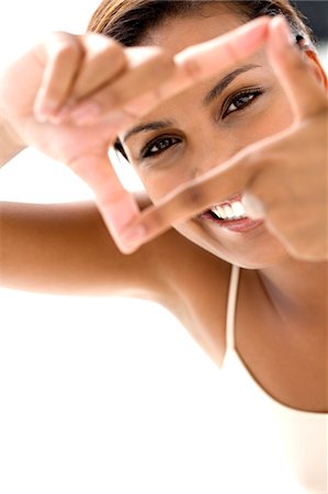 Portrait of a young smiling woman making a frame with her fingers Stock Photo - Premium Royalty-Free, Code: 6108-05857403