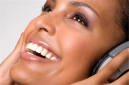 Portrait of a young smiling woman, listening to music with headphones Stock Photo - Premium Royalty-Free, Code: 6108-05857419