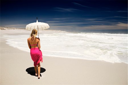 Jeune femme en bikini et paréo avec parasol sur la plage, vue arrière Photographie de stock - Premium Libres de Droits, Code: 6108-05857634