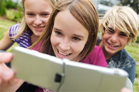 simsearch:6108-05857785,k - 2 smiling teenage girls and boy using camera phone, outdoors Stock Photo - Premium Royalty-Free, Code: 6108-05857740