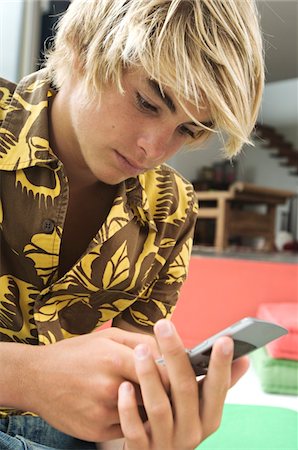 Teenage boy using mobile phone Stock Photo - Premium Royalty-Free, Code: 6108-05857762