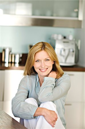 Woman smiling for the camera in kitchen Stock Photo - Premium Royalty-Free, Code: 6108-05857700