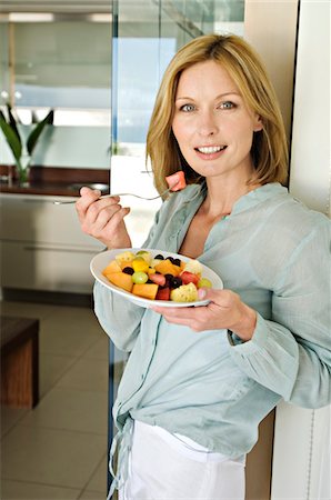 peace sign and woman - Woman eating fruit salad Stock Photo - Premium Royalty-Free, Code: 6108-05857708