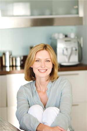 Woman smiling for the camera in kitchen Stock Photo - Premium Royalty-Free, Code: 6108-05857728