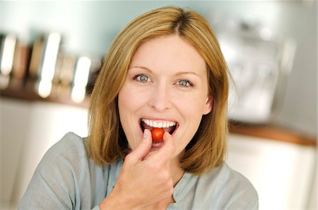 régime - Portrait d'une femme qui mange des tomates-cerises Photographie de stock - Premium Libres de Droits, Code: 6108-05857737