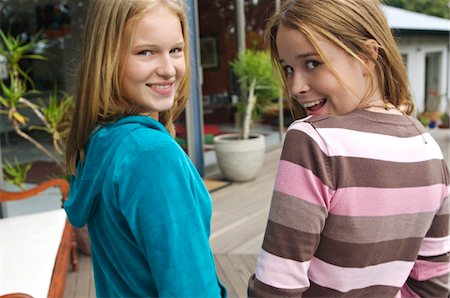 2 smiling teenage girls looking over shoulders Foto de stock - Royalty Free Premium, Número: 6108-05857818