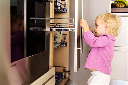 danger - Little girl opening cabinets in kitchen, indoors Stock Photo - Premium Royalty-Free, Code: 6108-05857990