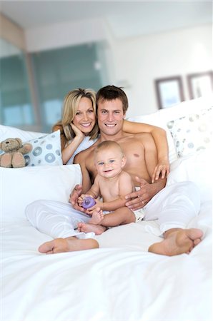 simsearch:6108-05857936,k - Young couple and baby in living room, looking at the camera, indoors Stock Photo - Premium Royalty-Free, Code: 6108-05857920