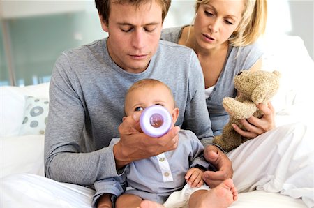 simsearch:6108-05857913,k - Young couple and baby sitting indoors, father feeding his son Stock Photo - Premium Royalty-Free, Code: 6108-05857931