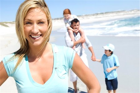 family group vacation - Parents and two children walking on the beach, woman in foreground, outdoors Stock Photo - Premium Royalty-Free, Code: 6108-05858062