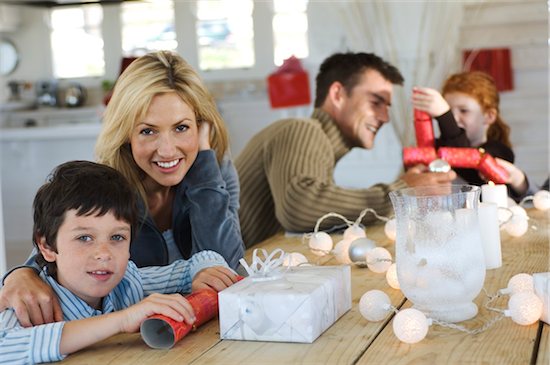 Couple ad three children sitting around table, exchanging Christmas presents, indoors Stock Photo - Premium Royalty-Free, Image code: 6108-05858005