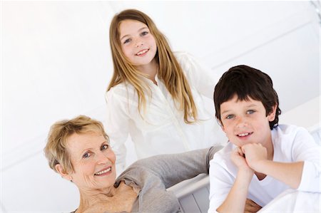 Senior woman and two children smiling for the camera, indoors Stock Photo - Premium Royalty-Free, Code: 6108-05858145