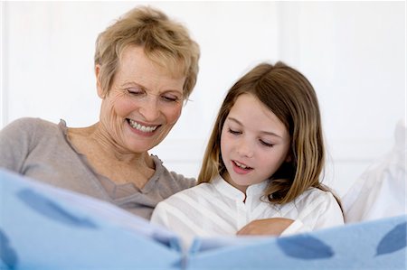 Senior woman and little girl in bed, looking at photograph album Foto de stock - Sin royalties Premium, Código: 6108-05858176