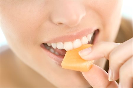 simsearch:6108-05857359,k - Portrait of a young woman eating a piece of melon, close-up, indoors Stock Photo - Premium Royalty-Free, Code: 6108-05858355