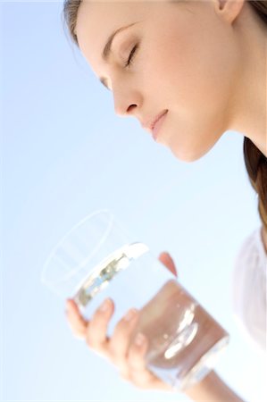 face, eyes closed, looking up - Portrait d'une jeune femme tenant un verre d'eau, à l'extérieur Photographie de stock - Premium Libres de Droits, Code: 6108-05858383