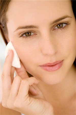 removes eye makeup - Portrait of a woman using a cleansing cotton on her cheek, indoors Stock Photo - Premium Royalty-Free, Code: 6108-05858380