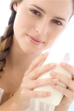 Portrait of a young woman holding a bottle of milk, indoors Stock Photo - Premium Royalty-Free, Code: 6108-05858333