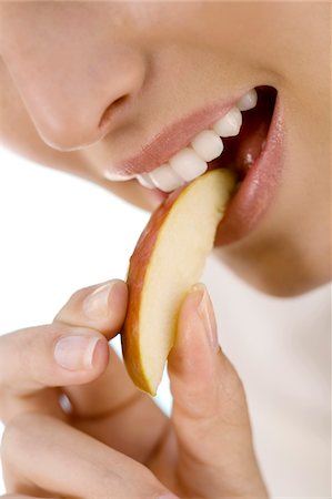 Portrait d'une jeune femme mangeant un morceau de pomme, à l'intérieur Photographie de stock - Premium Libres de Droits, Code: 6108-05858335