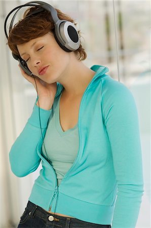 Portrait of a young woman, listening to music with headphones Stock Photo - Premium Royalty-Free, Code: 6108-05858551