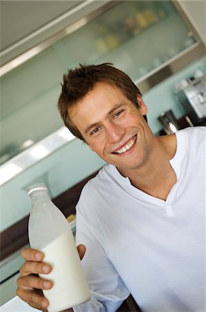 Portrait of a young smiling man holding bottle of milk Stock Photo - Premium Royalty-Free, Code: 6108-05858533