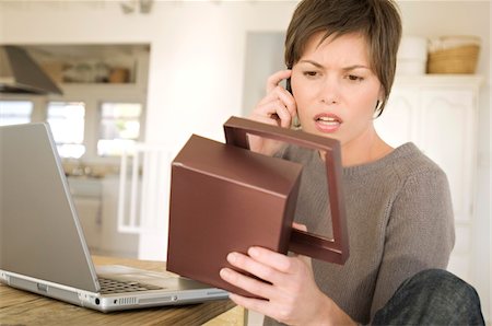 sad woman with short hair - Young woman with laptop, phoning, holding box Stock Photo - Premium Royalty-Free, Code: 6108-05858664