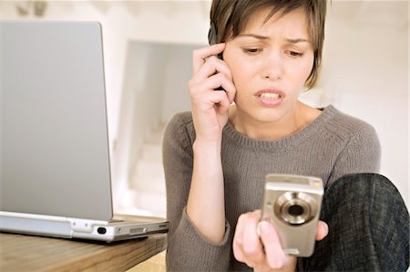 Young woman phoning, holding digital camera Stock Photo - Premium Royalty-Free, Code: 6108-05858670