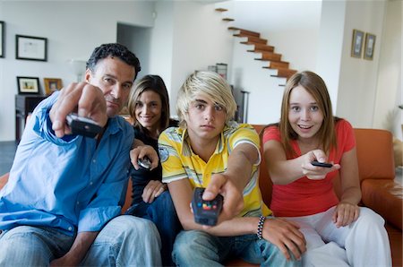 parents and children watching television - Parents and 2 teens using remote-controls Stock Photo - Premium Royalty-Free, Code: 6108-05858675