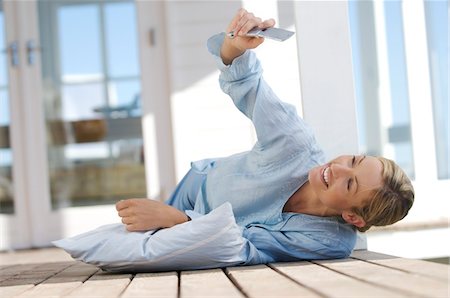 Young woman lying on floor, using mobile phone Stock Photo - Premium Royalty-Free, Code: 6108-05858616