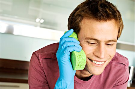 Portrait of a man making a phone call with a sponge Stock Photo - Premium Royalty-Free, Code: 6108-05858622