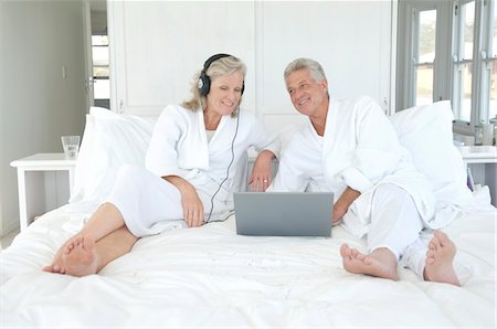 Couple in bathrobe using laptop in bed Stock Photo - Premium Royalty-Free, Code: 6108-05858799