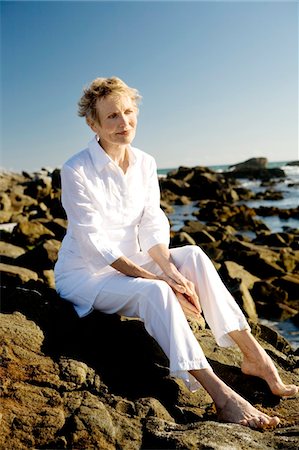 Senior woman sitting on seaside rocks Stock Photo - Premium Royalty-Free, Code: 6108-05858850
