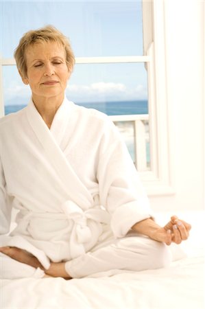 respiring - Senior woman sitting cross-legged on bed Stock Photo - Premium Royalty-Free, Code: 6108-05858863